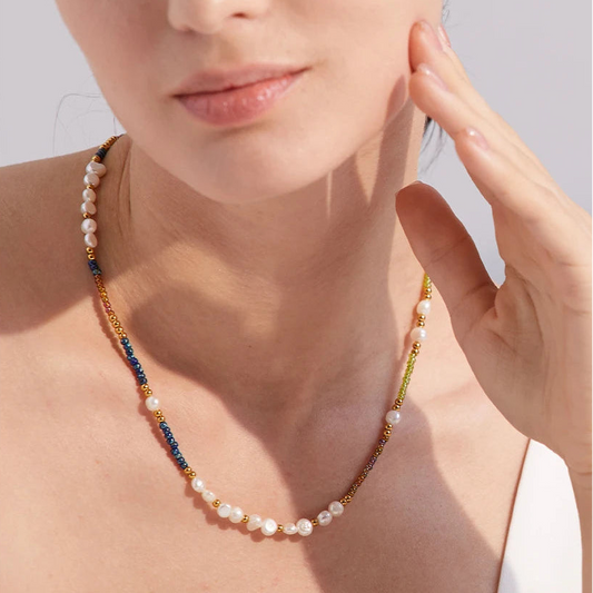 Pearl necklace worn by a person with a neutral background