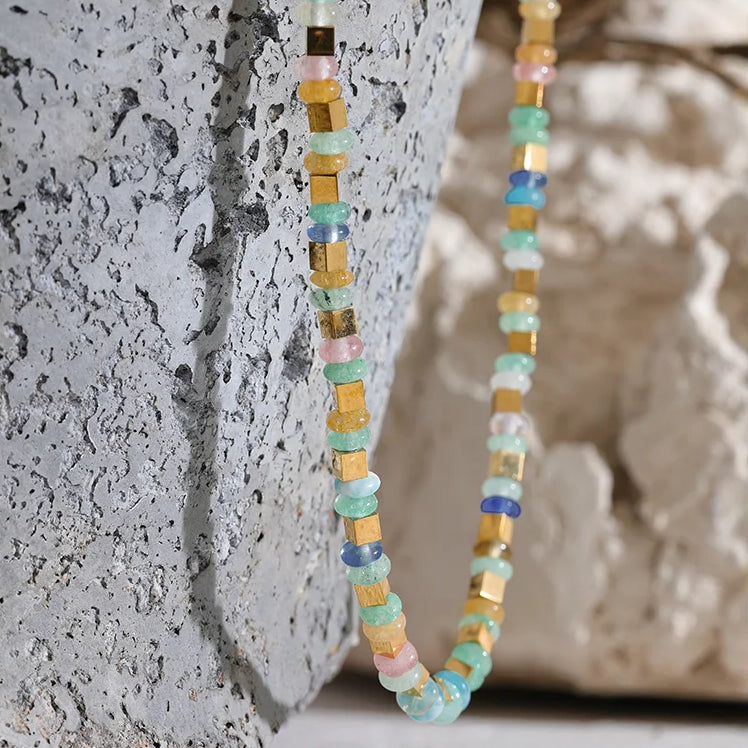 Multicolored beaded necklace against a textured stone background