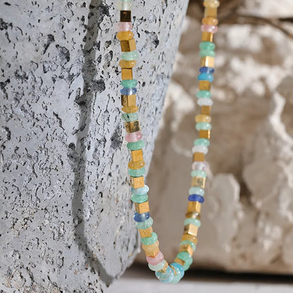 Multicolored beaded necklace against a textured stone background