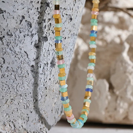Multicolored beaded necklace against a textured stone background